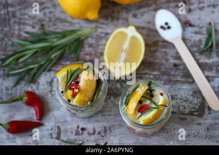 Fermented lemons in jars of salt, chili pepper and rosemary. Probiotics Fermented food. Pickled lemons. Stock Photo