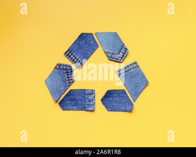 Reuse, reduce, recycle concept background. Recycle symbol made from old jeans on yellow background. Top view or flat lay. Stock Photo