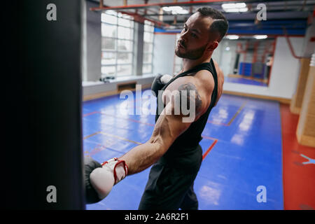 serious boxer with tatoo on his arm spending time at gym. close up photo. leisure concept Stock Photo