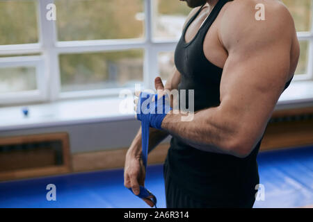 young strong sportsman protecting his palms during workout, safety, protection. close up cropped side view photo Stock Photo
