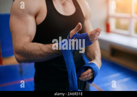 young strong man using bandage for workout, close up cropped photo. necessary tool for boxer, preparation for training Stock Photo