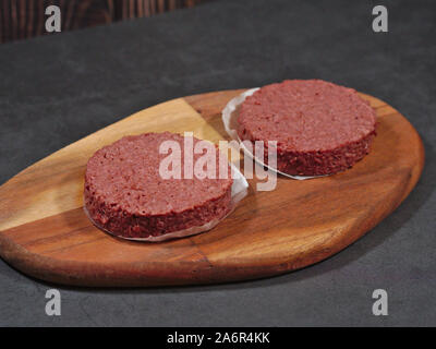Raw vegan plant based burgers on cutting board Stock Photo