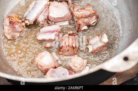 Pieces of beef on bones stew in a cauldron. Preparing of Chorba soup on open fire, traditional meal for many national cuisines Stock Photo