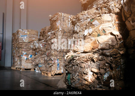 Used cardboard polyethylene and plastic pressed into bales at finished products warehouse on modern waste sorting and processing plant. Stock Photo