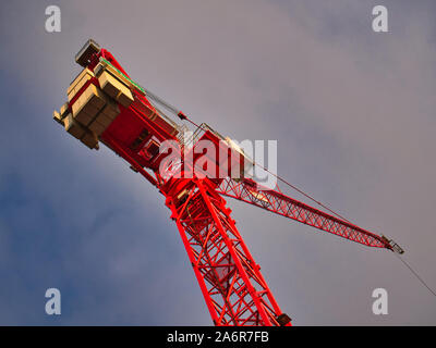 A red tower crane against a blue and grey evening sky. The counter balancing blocks are visible on the left. Stock Photo