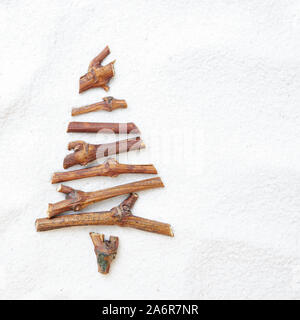 Flat lay stylized Christmas tree made of small twigs on snow background. Space for text Stock Photo