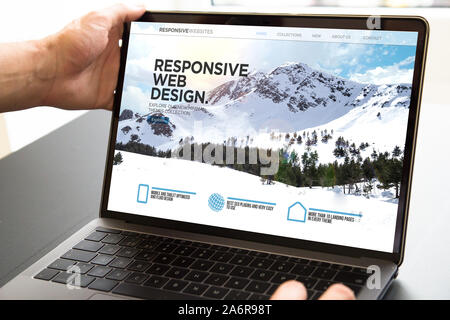 user opening laptop showing responsive web design website Stock Photo