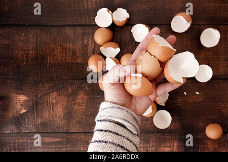 Hands holding brown eggshells, wood background Stock Photo