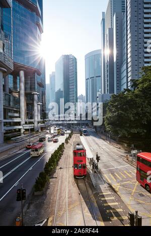 Red double-decker tram on city street against skyscrapers. Traffic in downtown financial area in Hong Kong, China. Stock Photo