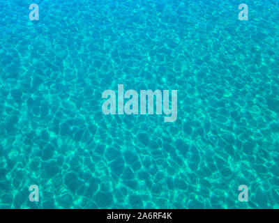 Aerial view of a sandy seabed, crystal clear blue water, reflections of the sun cause ripples on the sea surface. Texture and background. Pool Stock Photo