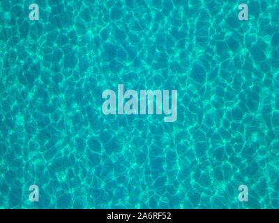 Aerial view of a sandy seabed, crystal clear blue water, reflections of the sun cause ripples on the sea surface. Texture and background. Pool Stock Photo