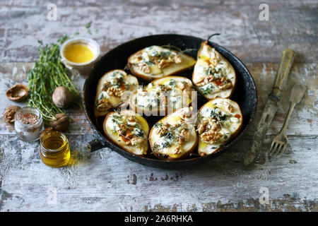 Halved Pears in a pan baked with Dorblu cheese, honey, walnuts and thyme. French cuisine. Keto diet. Selective focus. Stock Photo