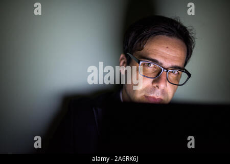 Handsome Persian businessman using laptop in dark room Stock Photo