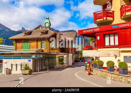 Wengen, Switzerland - October 10, 2019 : Railway train station old wooden house with clock tower, town street view and autumn mountains Stock Photo