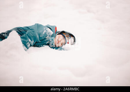 Happy boy lying in snow during winter Stock Photo