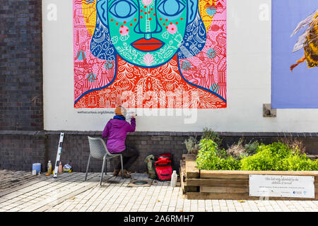 Artist writing on wall painting on We the Curious building, Bristol, UK Stock Photo