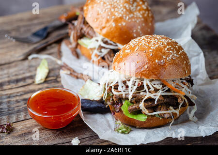 Pulled beef burger with cabbage salad and bbq sauce on paper Stock Photo