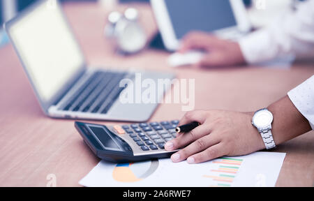 businessman with hand holding pen working on calculator to calculate business information data Stock Photo