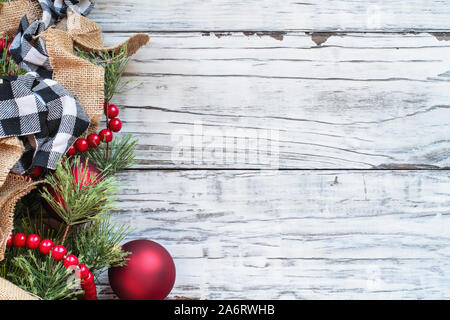 Christmas background with holiday trimmings of pine tree branches, ornaments, black and white buffalo check ribbon, burlap and red bead garland.. Top Stock Photo