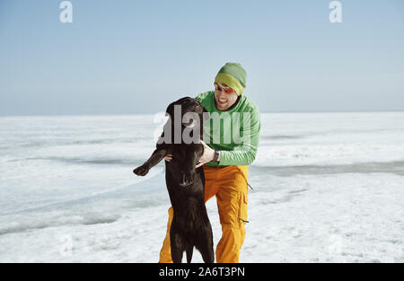 Young adult man outdoors with his dog having fun in winter landscape Stock Photo
