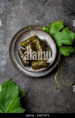 Traditional Middle Eastern dolma or tolma. Grape leaves stuffed with meat and rice. On Gray plate, gray concrete background Stock Photo