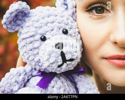 Pretty, young woman holding a stuffed toy in the background of yellow foliage. Close-up, outside Stock Photo