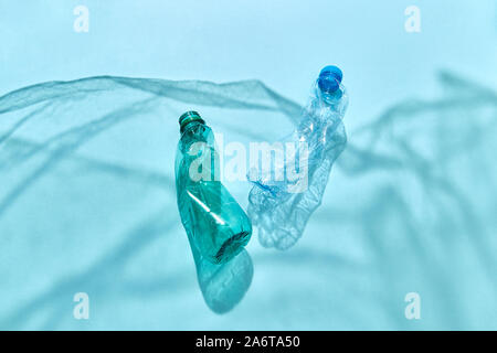 Two plastic used bottles floating in the ocean shadows waves from polyethylene foil with copy space. Concept of enviromental pollution of world ocean. Stock Photo