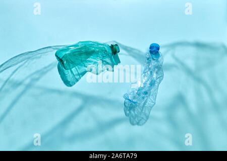 Ocean waves from shadows of polyethylene foil with floating bottles underwater on a pastel blue background, copy space. Concept of enviromental pollut Stock Photo