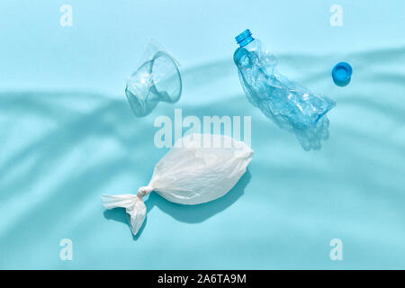 Fish in polythene bag and plastic bottles are floating under water from shadows on a pastel blue background, copy space. Ecological problem of polluti Stock Photo