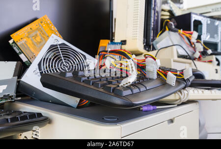 Computer hardware components on e-waste pile. Discarded or obsolete spare parts and accessories. Keyboards, printers, fans, colored cables, connectors. Stock Photo