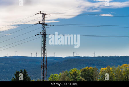 Electricity production and transmission concept. Electric power tower. Wind farm turbines in morning landscape. Propellers silhouette. Climate changes. Stock Photo