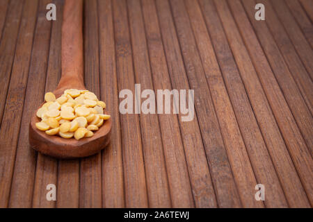 Picture of pigeon pea also known as toor dal in a wooden spoon. Isolated on brown background. Stock Photo