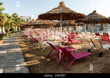 Ready and clean sun beds on a sandy beach at sunrise waiting to be used for sun bathing Stock Photo