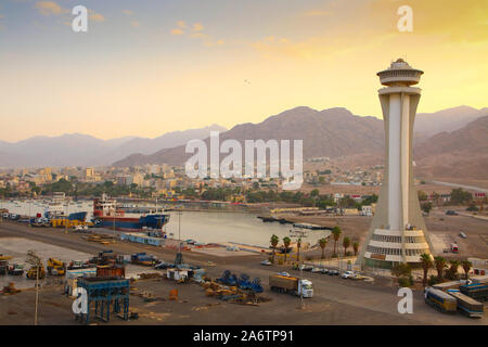Commercial Port of Aqaba, Jordan. Cargo ships, and shipping equipment in the foreground with the city and mountains in the background. Stock Photo