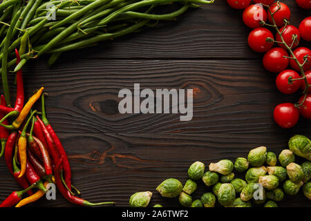 top view of chili peppers, cherry tomatoes, green peas, brussels sprouts on wooden table Stock Photo