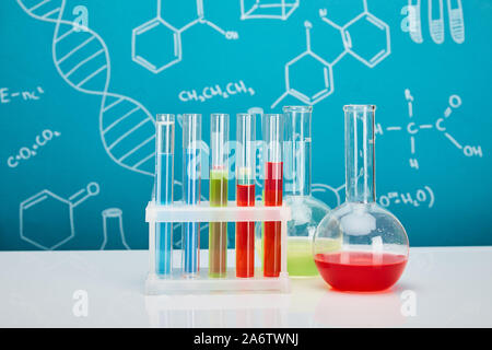 glass test tubes and flasks with colorful liquid on blue background with molecular structure Stock Photo