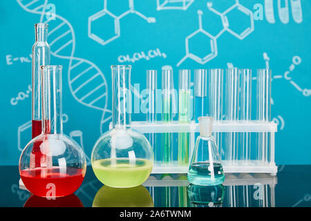 glass test tubes and flasks with colorful liquid on blue background with molecular structure Stock Photo