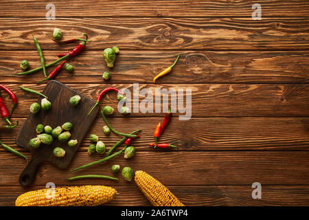 top view of corn, chili peppers, green peas, brussels sprouts on cutting board Stock Photo