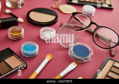 selective focus of cosmetic brushes near glasses on crimson Stock Photo