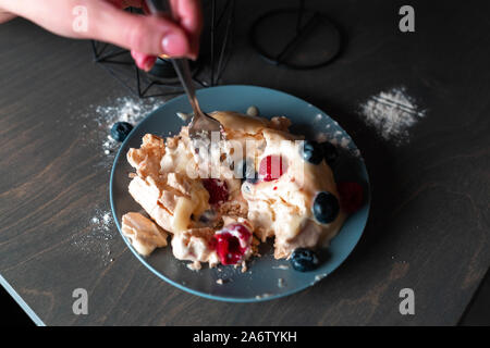 Pavlova Dessert Cake with Berries on grey Plate and wooden table. round Meringue with whipped cream, close up. Delicious Pavlova cake with fresh raspb Stock Photo