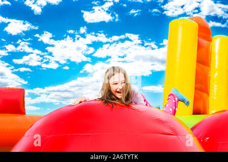 Happy little girl having lots of fun on a inflate castle while jumping. Stock Photo
