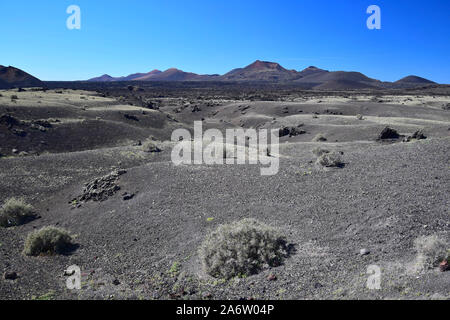 A barren landscape in Lanzarote with the volcanos of the Timanfaya national park in the back. Stock Photo