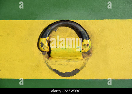 Background of a floor plate of yellow and green metal, to which a ring of metal is attached Stock Photo