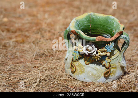 An old broken colored jug of clay lies on dry soil on the ground in Sicily Stock Photo