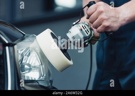 partial view of car cleaner polishing headlamp with buffer machine Stock Photo