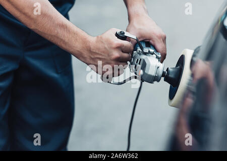 partial view of car cleaner polishing car with buffer machine Stock Photo