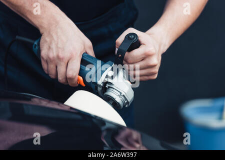 partial view of car cleaner polishing black car with buffer machine Stock Photo