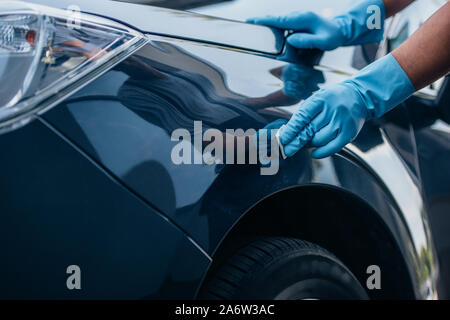 partial view of car cleaner in rubber gloves polishing car Stock Photo