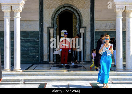 Guard soldier in national costume at the entrance of Mausoleum of Mohammed V and square with Hassan tower in Rabat on sunny day. Location: Rabat, Moro Stock Photo