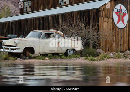 Vintage Texaco gas station with an antique car in front of a neglected building. Stock Photo